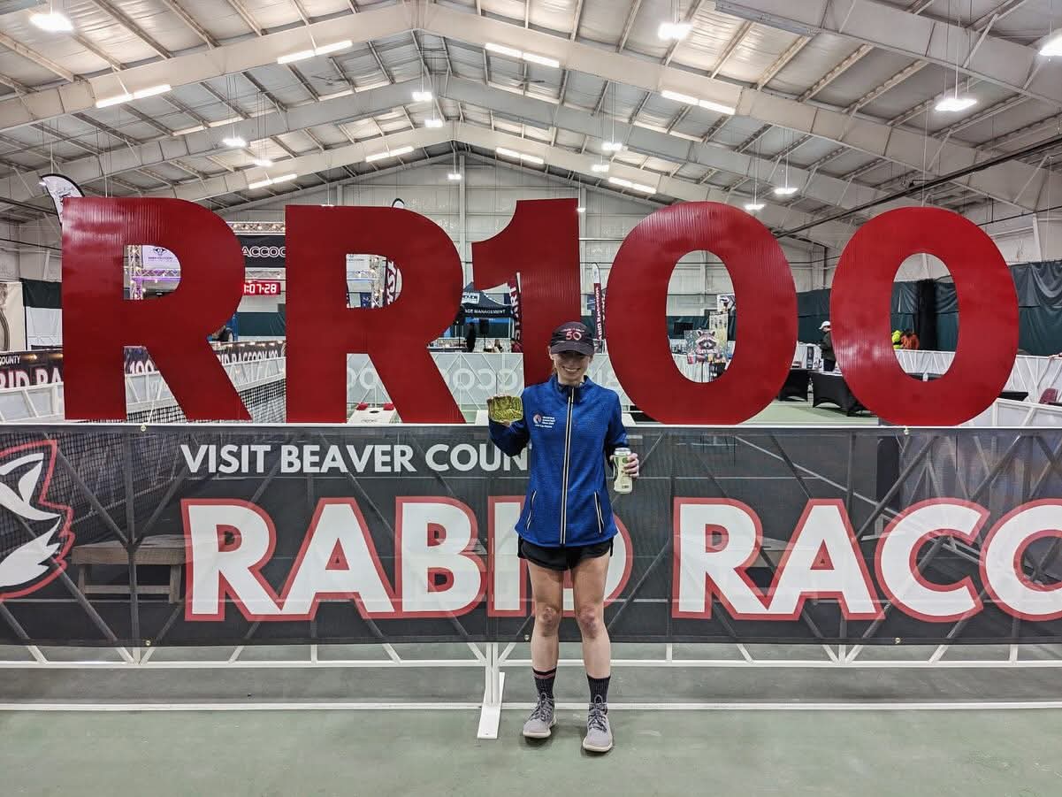 Runner poses with RR100 race sign
